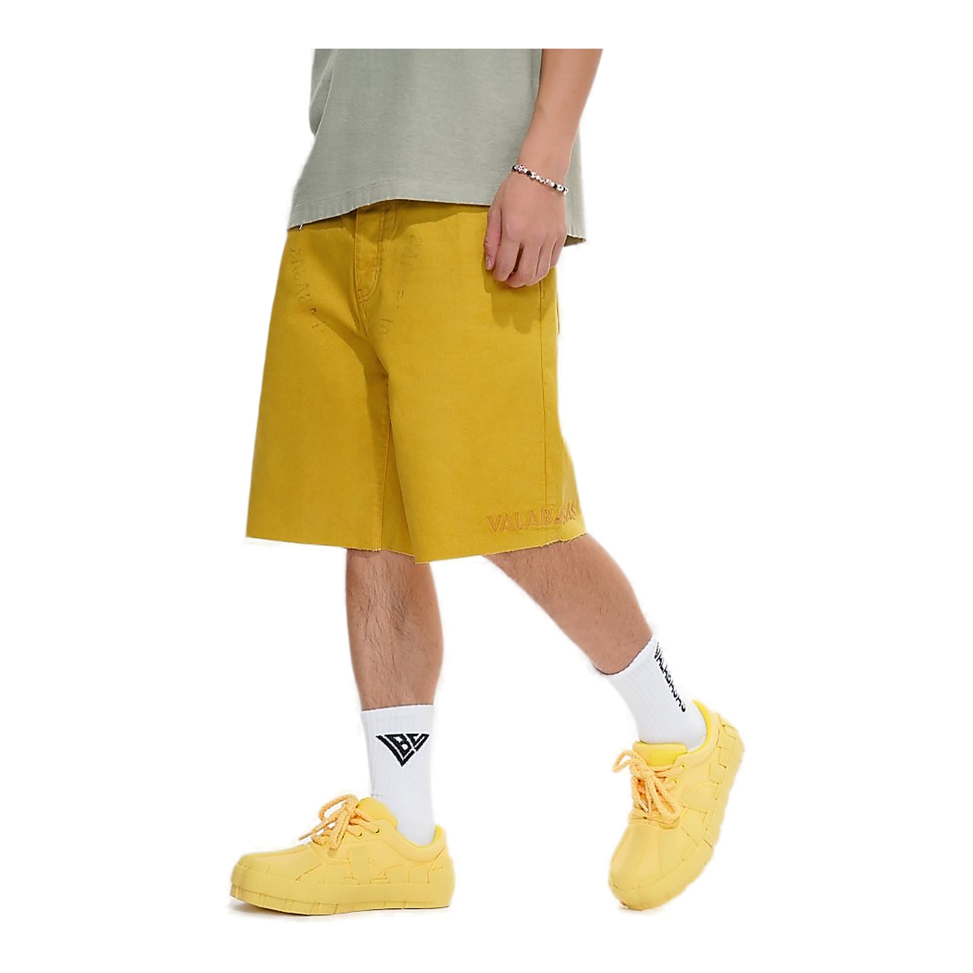 Person wearing mustard yellow shorts and shoes on a white background