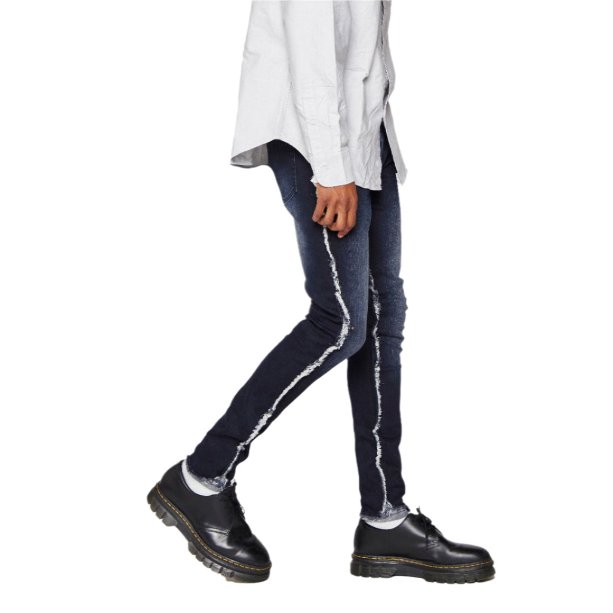 Person wearing dark blue jeans with white stripes and black shoes on a white background